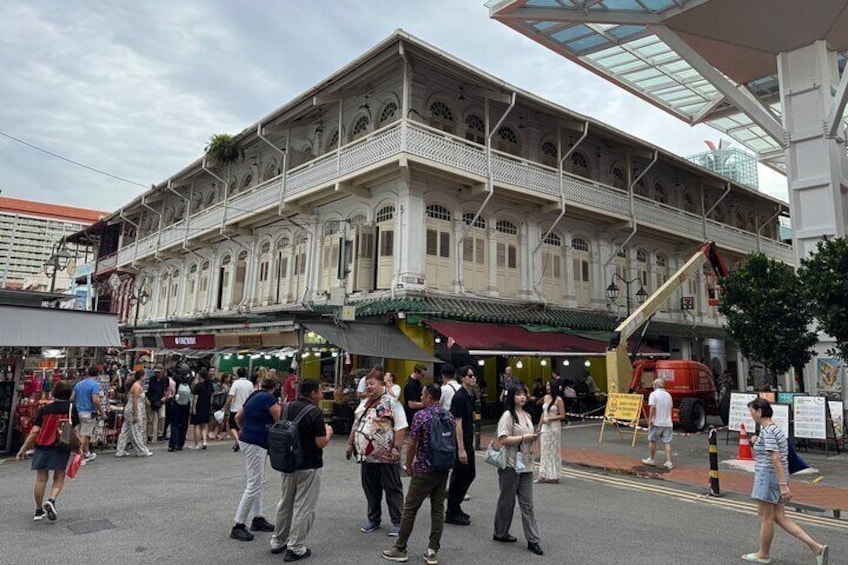 A busy street with people walking and a historic building with shops. 4