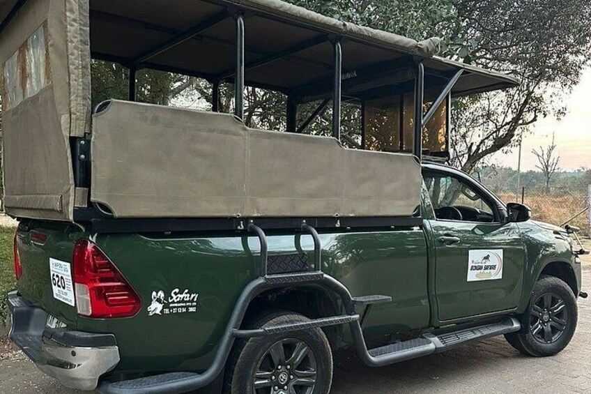 A green pickup truck with a cargo bed, parked under a shelter. 2