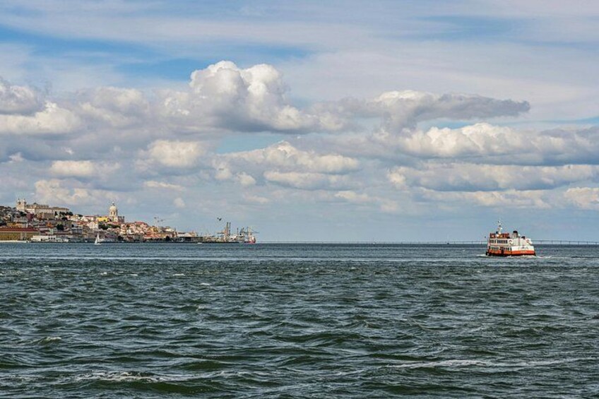 A coastal cityscape with a ferry in the distance, a bridge, and a clear sky. 5