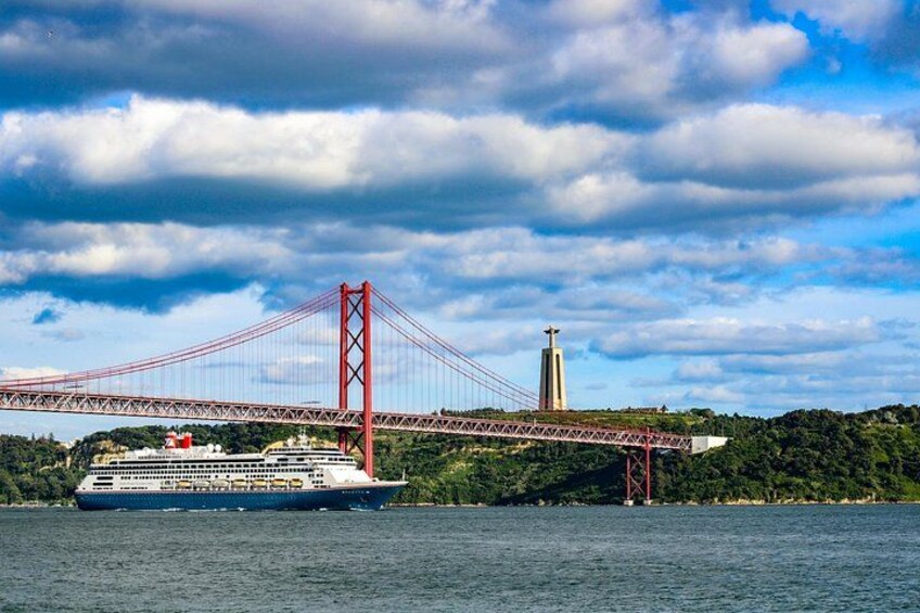 A cruise ship on a river, a red bridge, and a tower in the background. 1