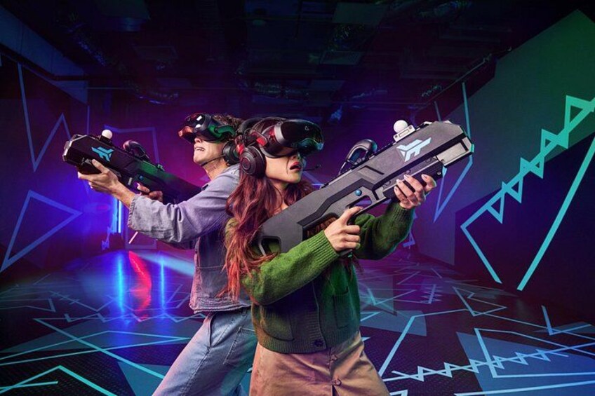 People wearing VR headsets holding futuristic-looking guns in a neon-lit room. 2