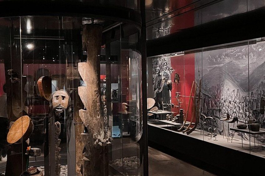 A museum exhibit with various artifacts and a large mural. 4