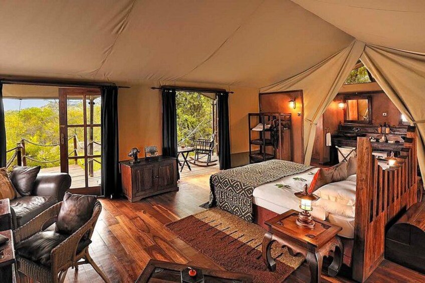A tented accommodation with a wooden floor, a sofa, a dining table, and a staircase. 5