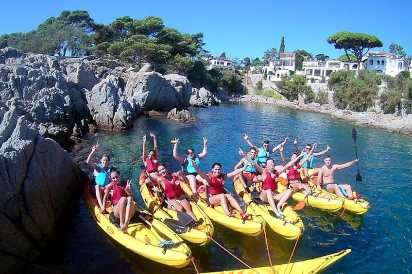 A group of people kayaking on a river surrounded by rocky terrain and buildings. 2