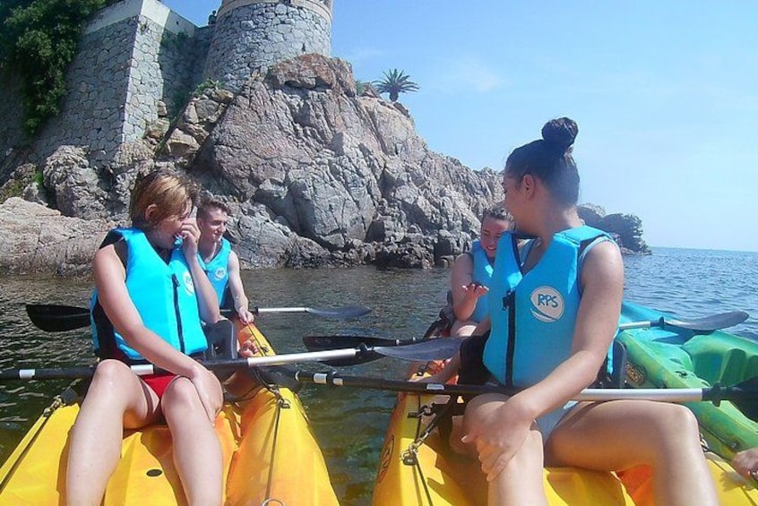People in kayaks on a calm body of water with rocky cliffs in the background. 3