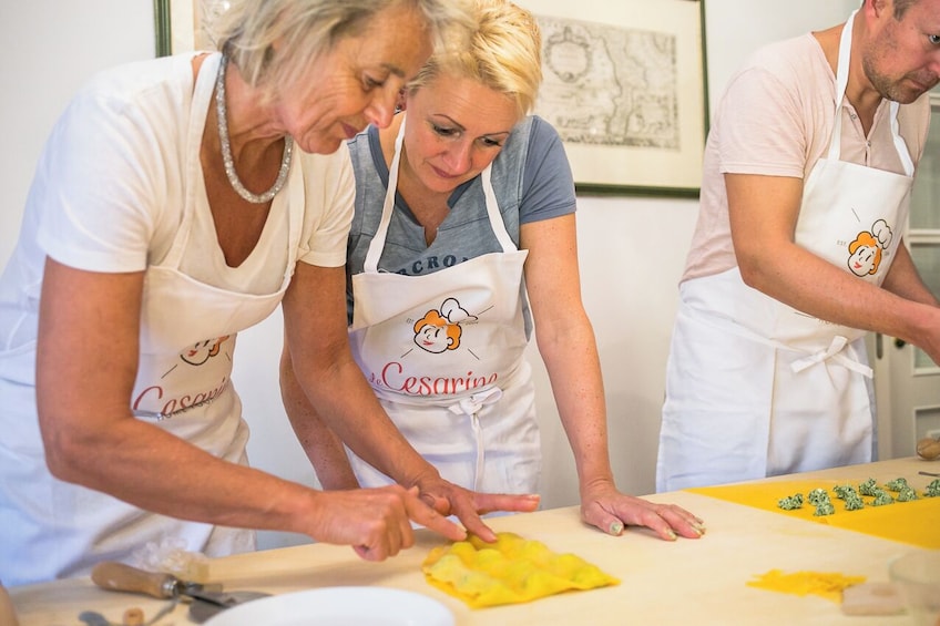 Three people wearing aprons with a cartoon character, working together in a kitchen. 2