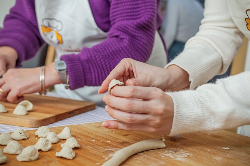 Hands shaping dough on a wooden board. 4