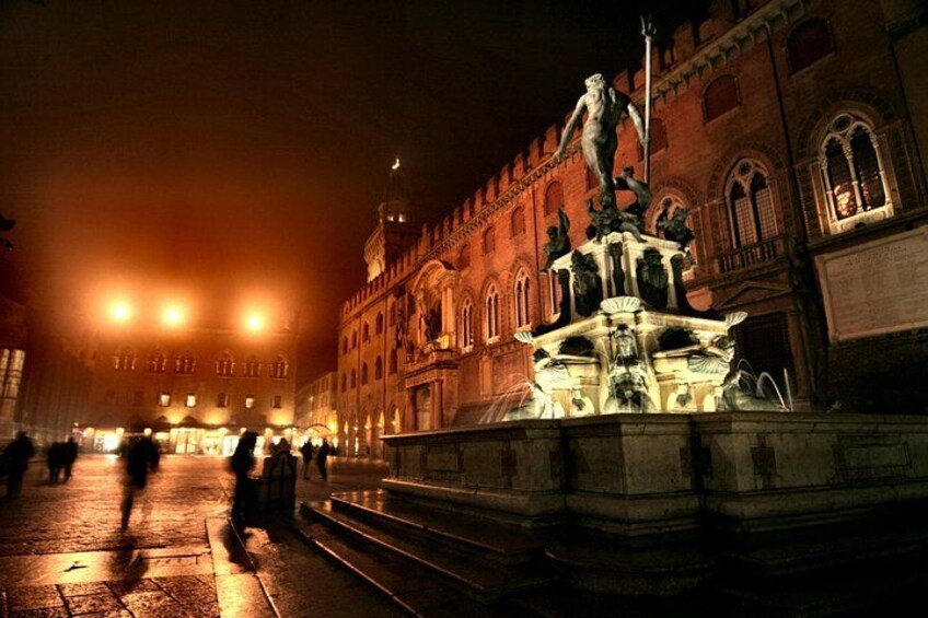 A nighttime city square with a prominent fountain and classical architecture. 1