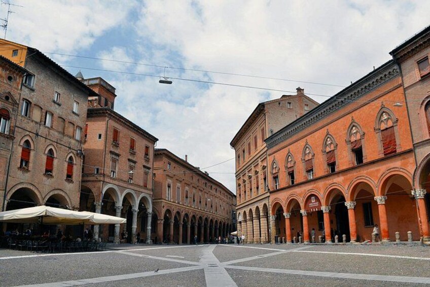 A street with buildings on both sides, featuring arches and a clear sky. 5