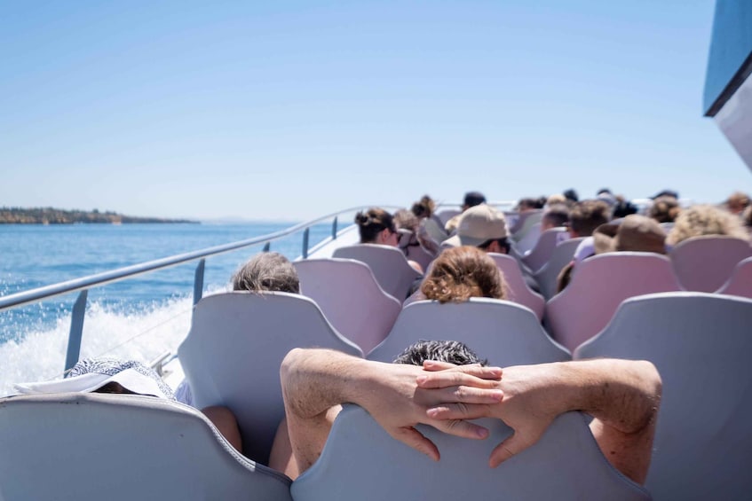 A boat with passengers seated, water in the background, and a distant shoreline. 4