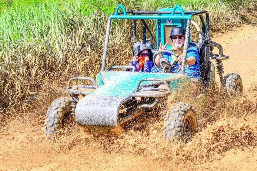 A vehicle driving through a field with people inside. 1