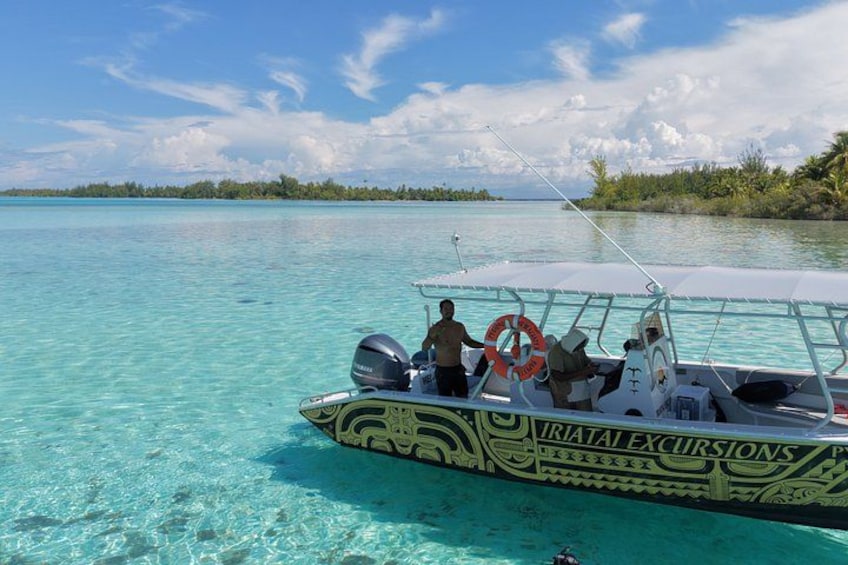 A boat with 'RIATAI EXCURSIONS' written on it, floating on clear turquoise water. 4