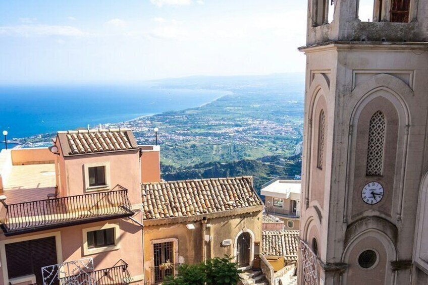 A coastal town with a prominent clock tower and terracotta-roofed buildings. 4