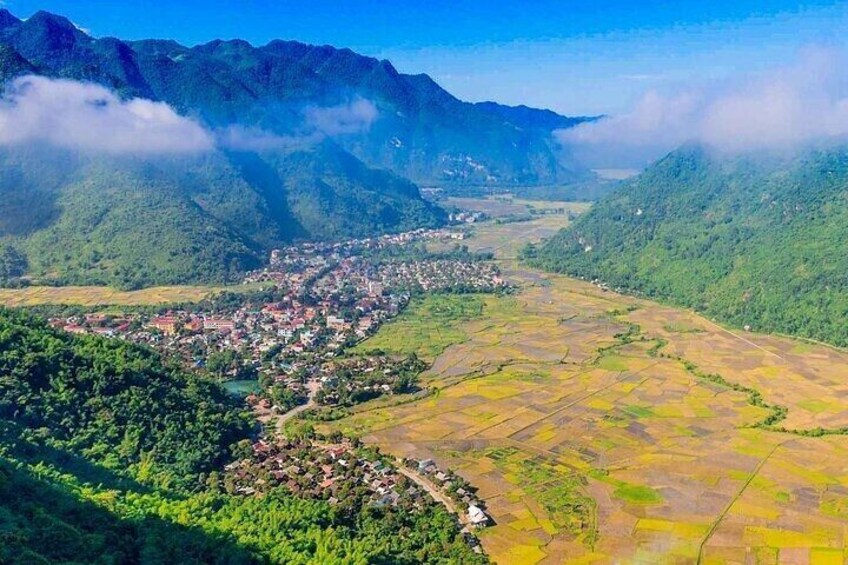 A mountainous landscape with a town nestled in the valley, terraced fields, and a river. 3