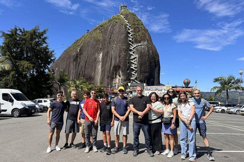 A group of people standing in a parking lot with a large rock formation in the background. 1
