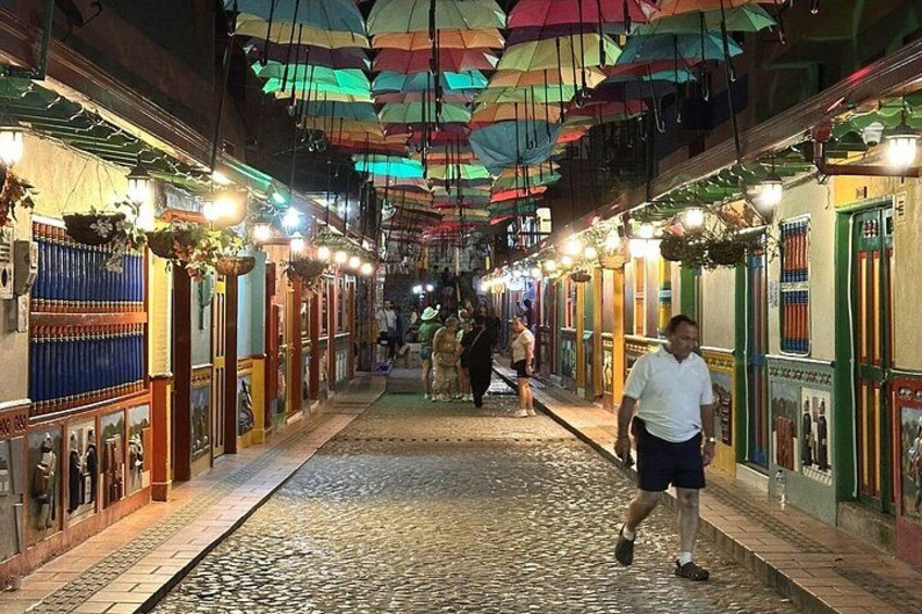A cobblestone street with colorful umbrellas and lanterns. 5