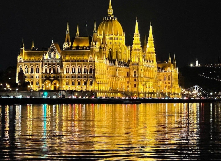 A grand illuminated building with a large dome and spires, reflecting on the water. 2