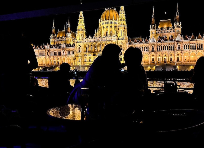 A group of people silhouetted against a brightly lit historic building at night. 1