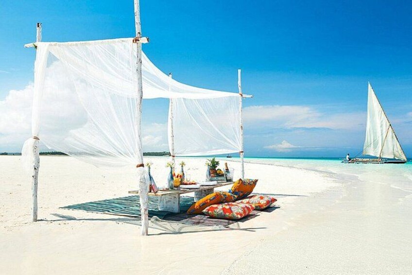 A beach with a white canopy, a boat, and a sailboat in the background. 2