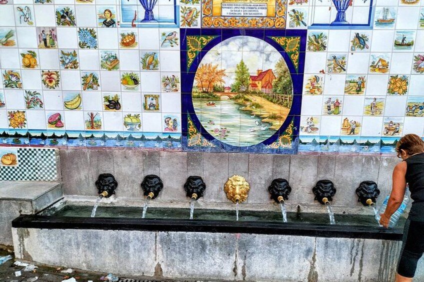 A tiled wall with a fountain and a woman standing by it. 3
