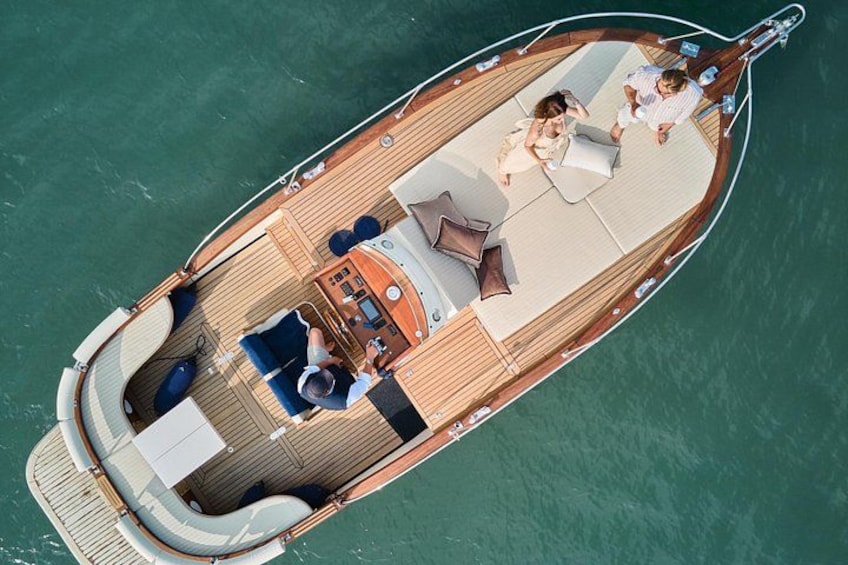 A boat with a wooden deck, lounge chairs, and a small table. 1