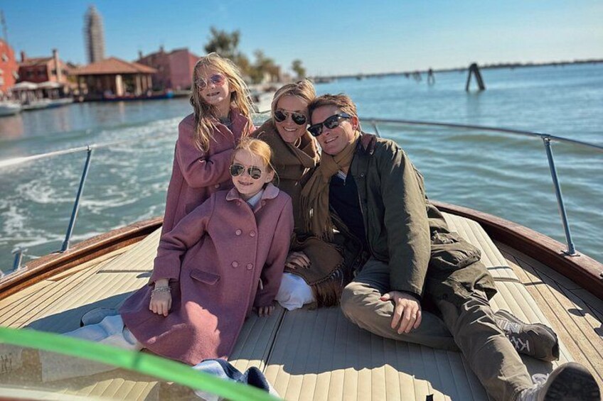 A family on a boat with a river and buildings in the background. 3