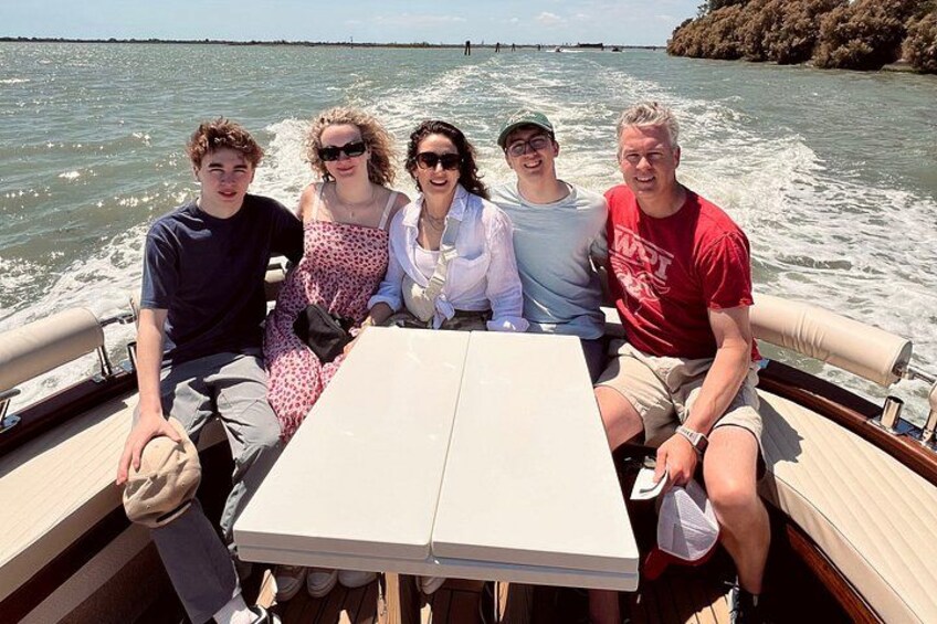 A group of people on a boat with a table in the center. 5