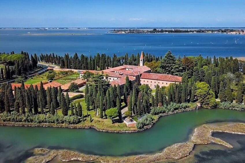A coastal estate with a prominent building, a body of water, and a dense tree line. 5