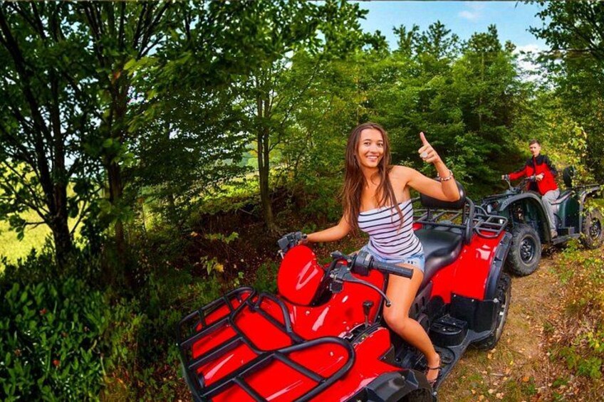 A person on a red ATV in a wooded area. 1
