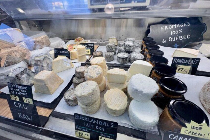 A cheese display with various types of cheese and labels indicating names and prices. 2