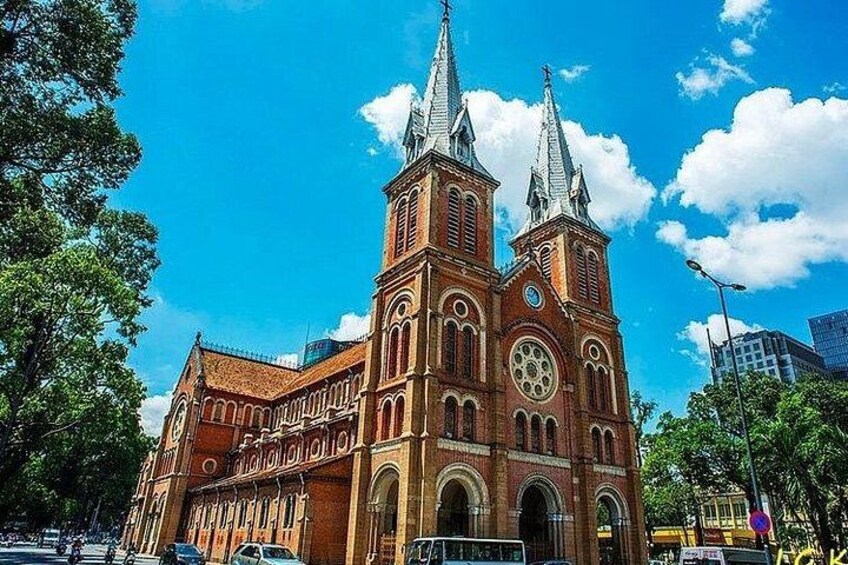 En stor kyrka byggd av tegel, med två höga tornspiror och ett klocktorn. 1