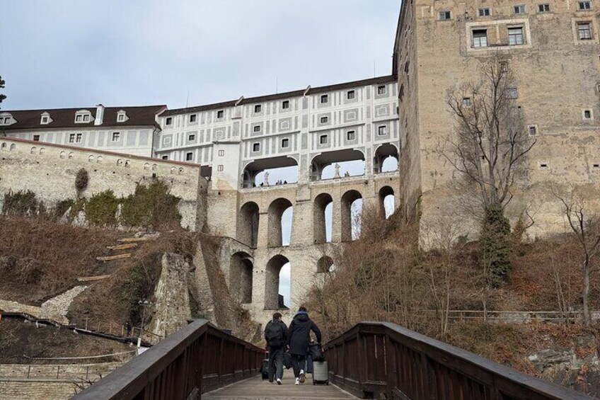 A bridge leading to a historic building with multiple arches and a large tower. 4