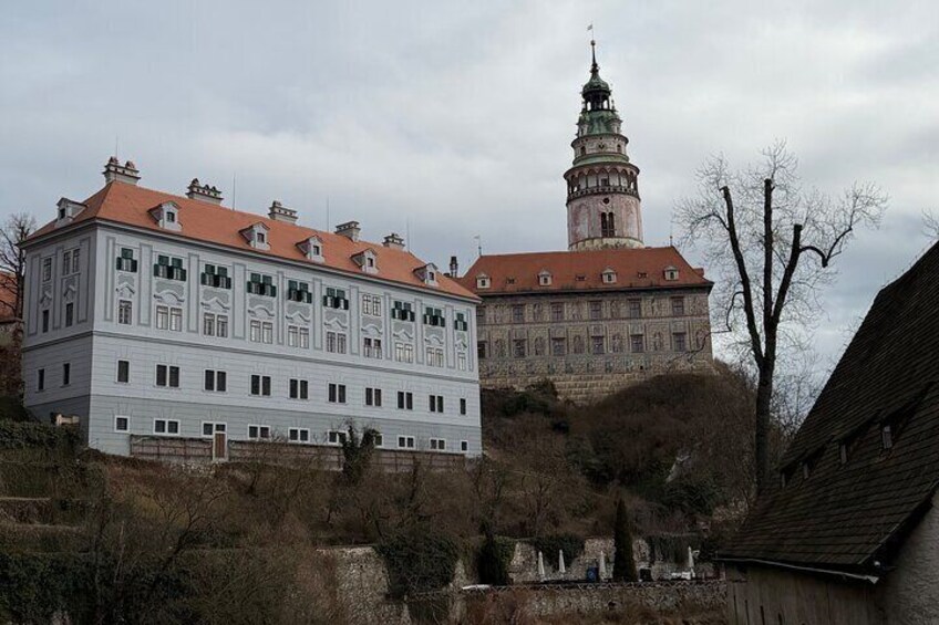 A large white building with a red roof, a tower with a spire, and a hill with sparse vegetation. 5