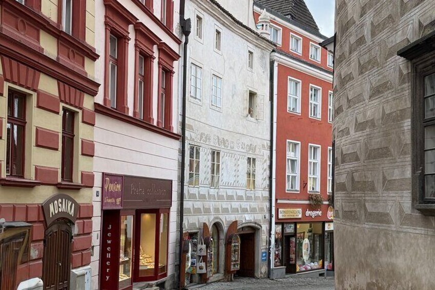 A street with buildings, including a jewelry store named 'Mosaika' and a shop called 'Peana collection'. 2