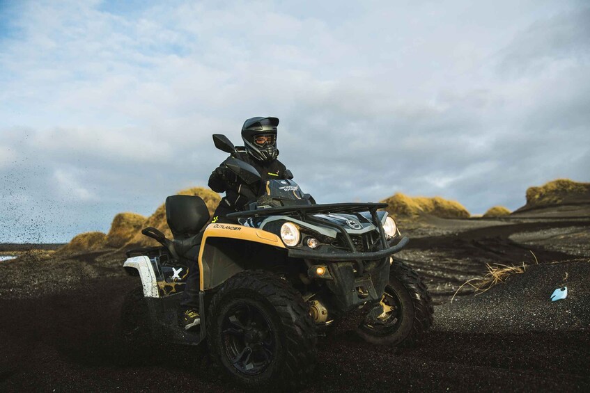 A person riding a black and yellow ATV on a rocky terrain. 2