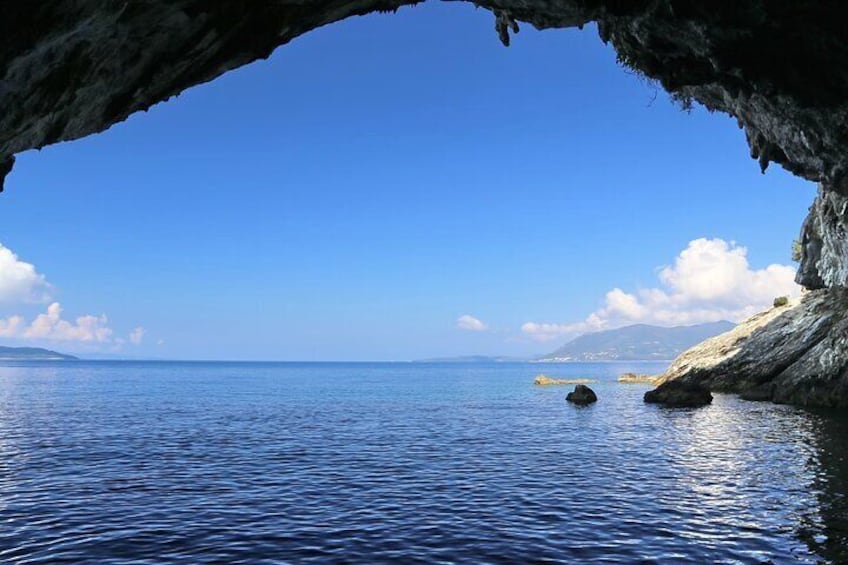 A clear blue sea, rocky coastline, and a cave entrance. 4