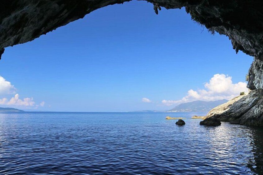 A coastal scene with a clear blue sky, calm sea, and rocky cliffs. 4