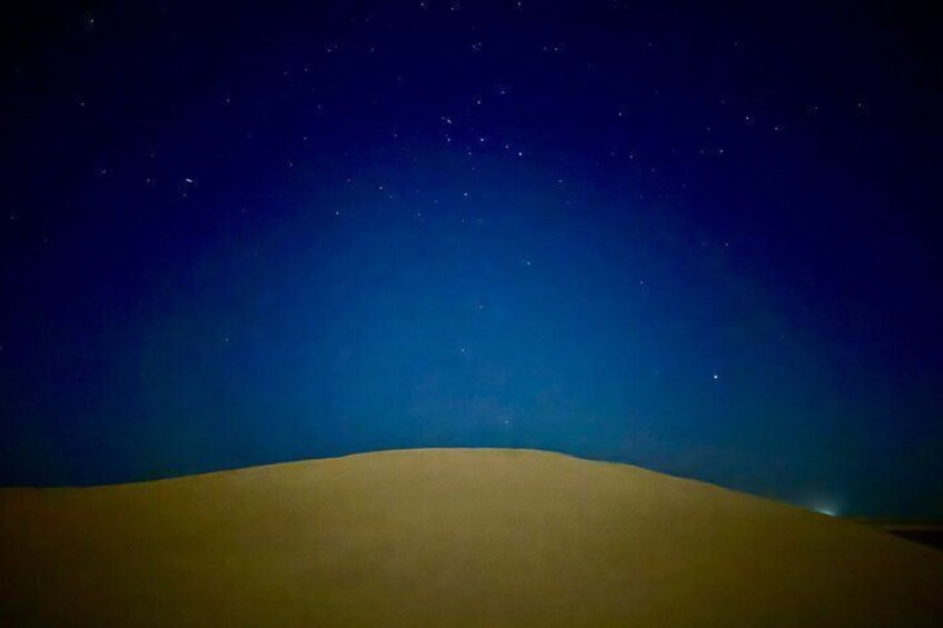 A desert landscape at night with a clear sky and stars. 3