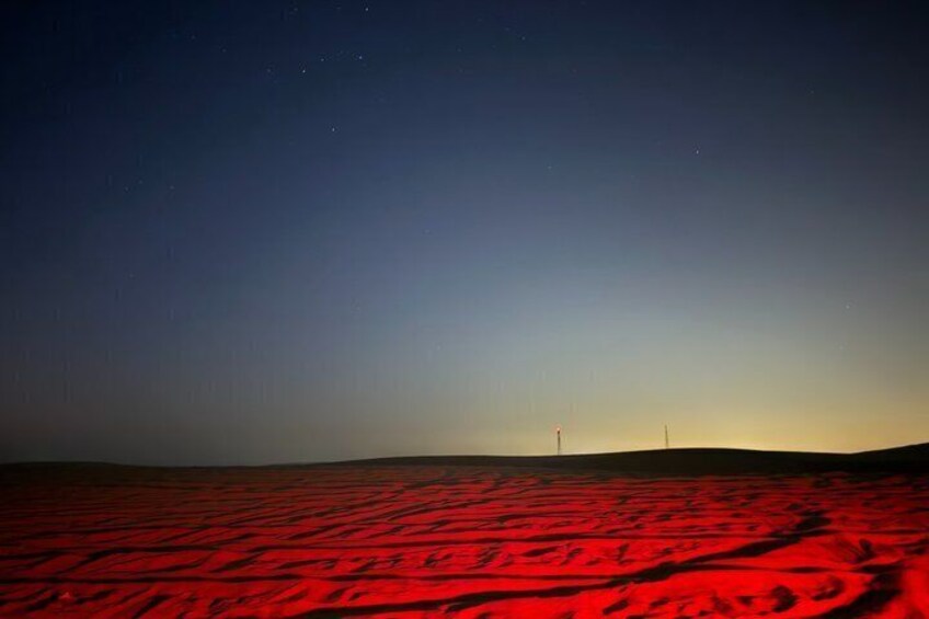 A red desert landscape with a clear sky and distant wind turbines. 2