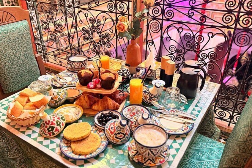 Une table dressée avec divers aliments pour le petit-déjeuner, notamment du pain, des viennoiseries et des boissons. 1