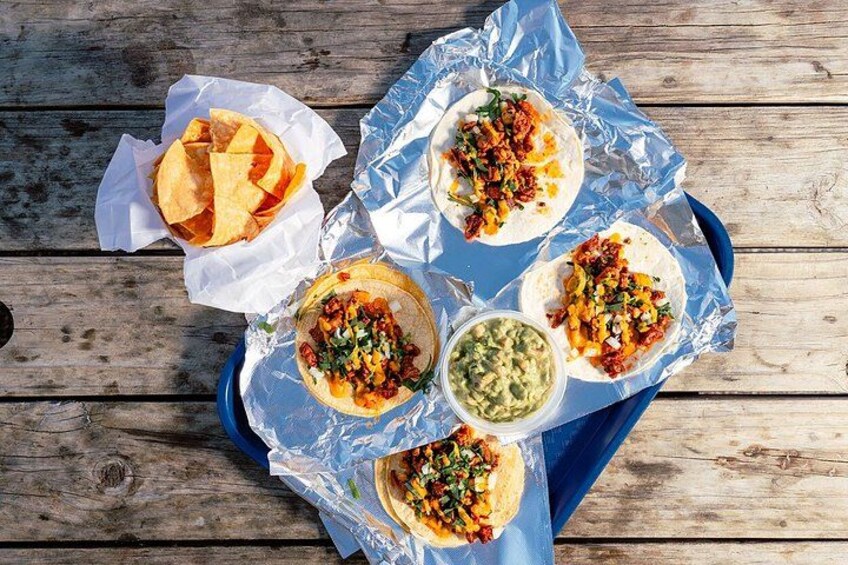 Tacos on a blue tray with guacamole and chips. 2