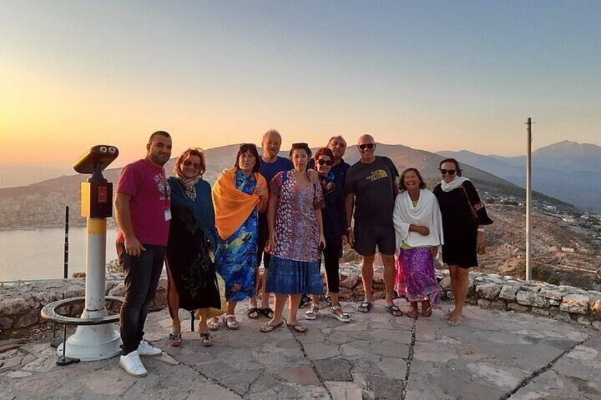 A group of people standing on a stone platform with a telescope, overlooking a valley and mountains. 2