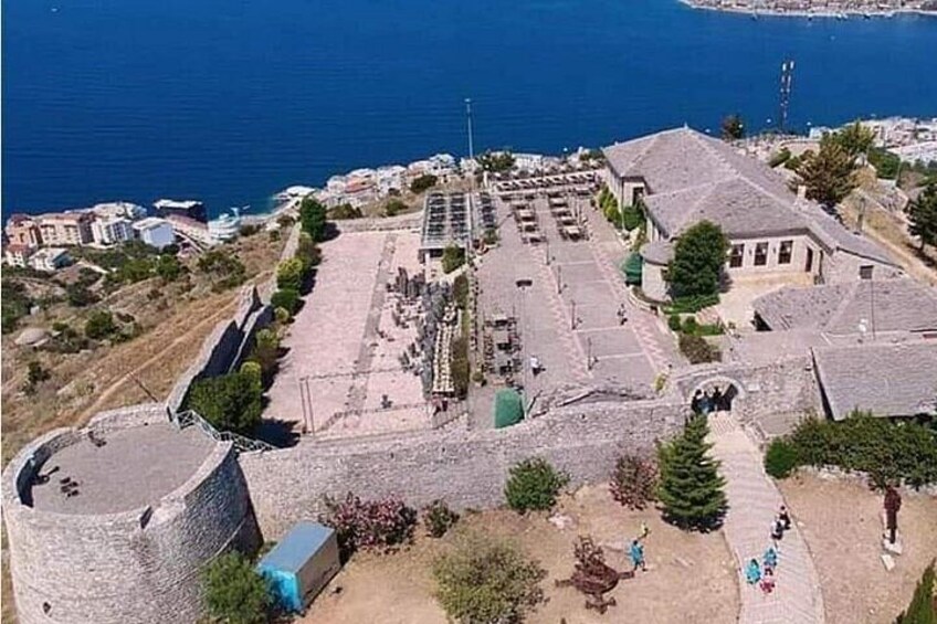 An aerial view of a coastal town with a fortified structure, a paved square, and buildings along the waterfront. 3