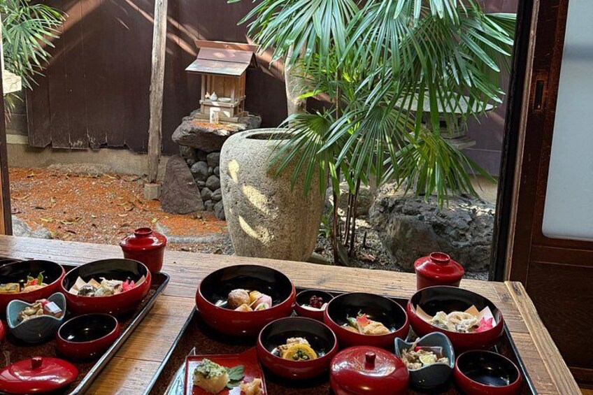 En traditionel japansk måltidsopstilling med røde skåle og en stenenlygte i baggrunden. 4