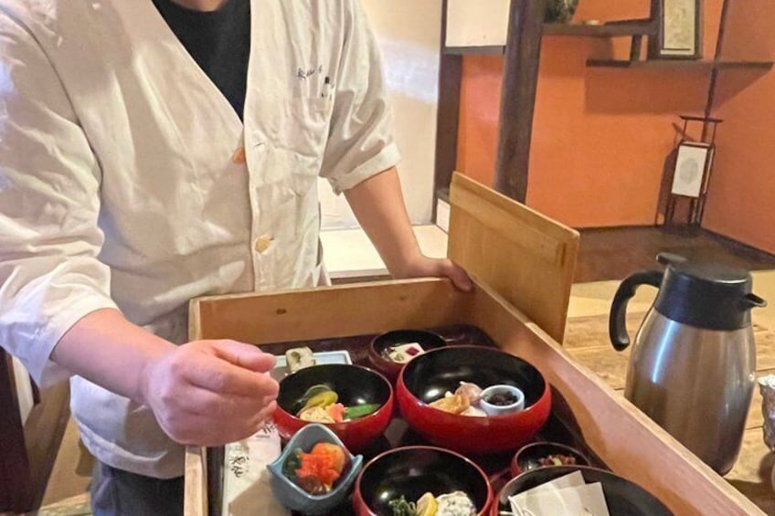 Una persona sirviendo comida de una caja de madera con diferentes platos. 3