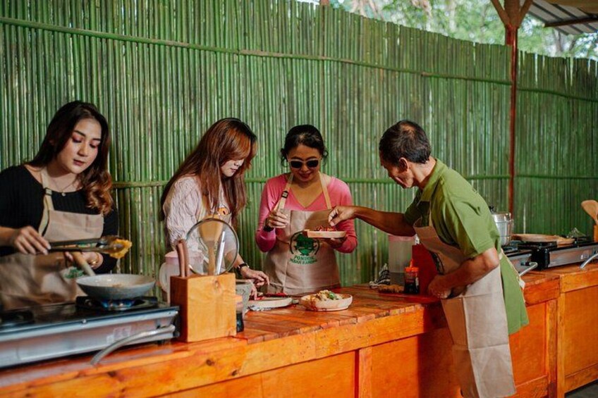 A group of people preparing food at an outdoor cooking station with a bamboo backdrop. 3