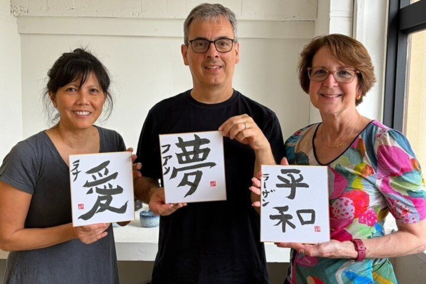 Three people holding signs with Japanese characters. 3