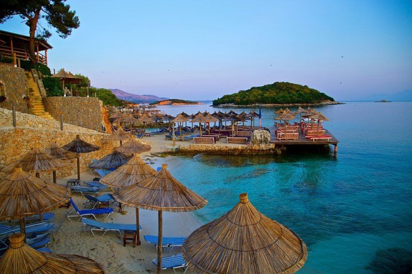 Une plage avec des parasols, des chaises longues et une jetée qui s’avance dans l’eau. 1