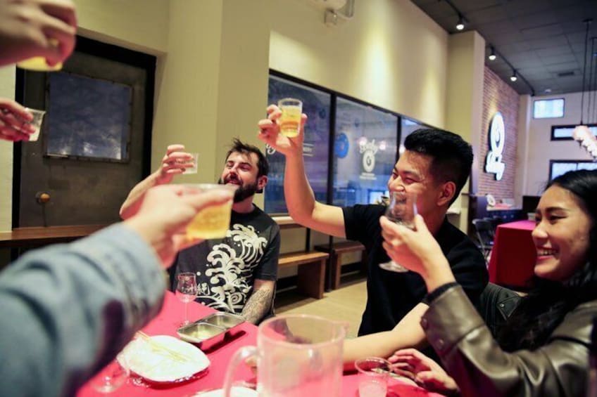 A group of people toasting with drinks at a table in a restaurant. 2
