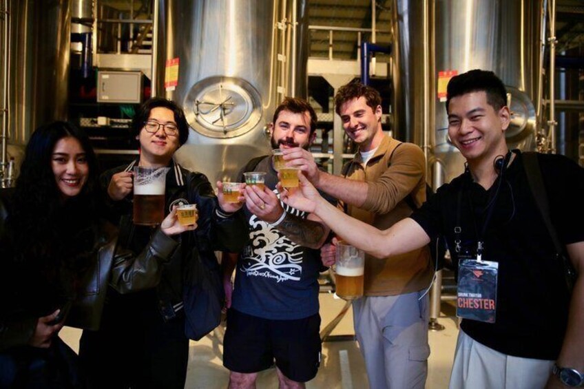 A group of people toasting with beer in a brewery setting. 5